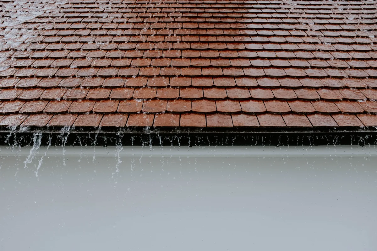 Rainwater running off a roof edge into an eavestrough